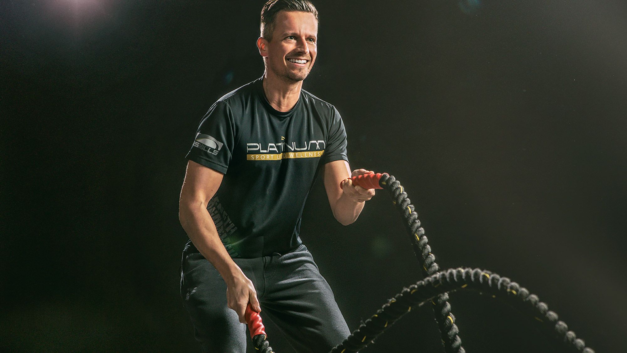 Dieses dynamische Fitnessfoto aufgenommen von dem Frankfurter Fotografen Fritz Philipp zeigt einen Sportler vor schwarzem Hintergrund der mit viel Spaß Seile schwingt