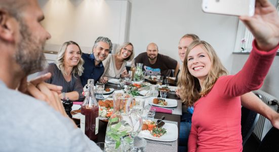 Die Imageaufnahme einer am Tisch sitzenden Gruppe beim Essen, die gerade ein Selfie macht, von dem Fotografen Fritz Phillipp aus Frankfurt im Rhein-Main-Gebiet