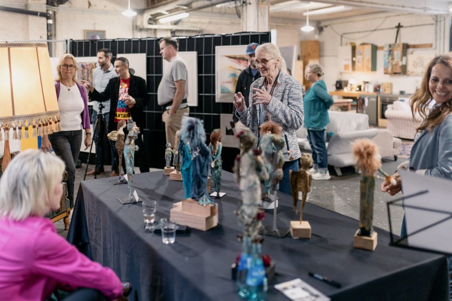 Ausstellerin im Gespräch mit Besuchern an einem Tisch mit Figuren und Skulpturen – KunstWerkStadt im Schärferaum Bad Homburg