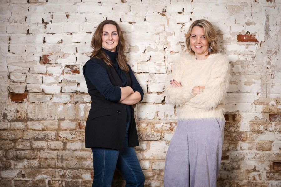 Zwei Frauen stehen mit verschränkten Armen vor einer Backsteinwand im Schärferaum – Portraitshooting Banking und Generation Alpha