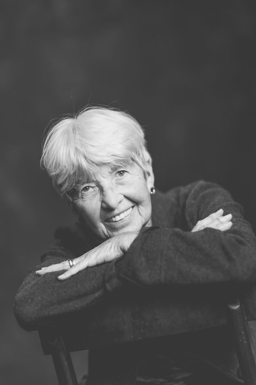 Schwarz-Weiß-Portrait einer älteren Frau, die lächelnd die Arme auf der Stuhllehne verschränkt – Schwarz-Weiß-Portrait bei der KunstWerkStadt im Schärferaum Bad Homburg