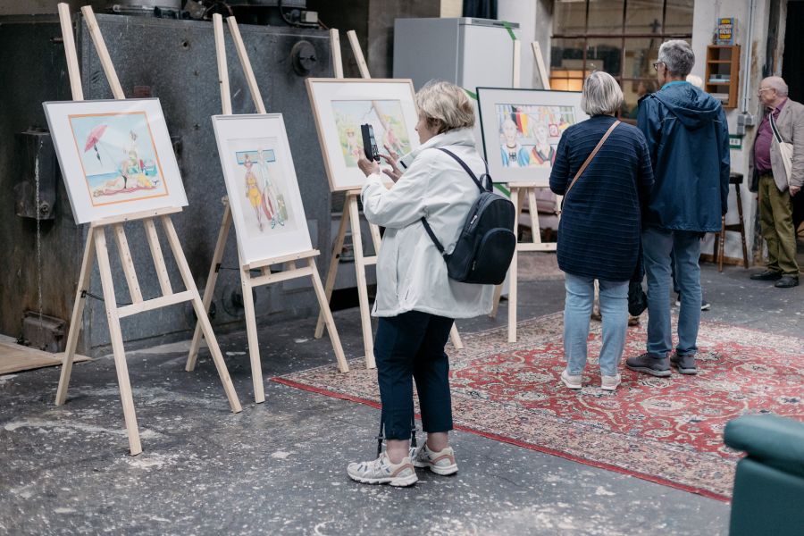Besucherin fotografiert Aquarelle auf Staffeleien, weitere Gäste im Hintergrund – KunstWerkStadt im Schärferaum Bad Homburg