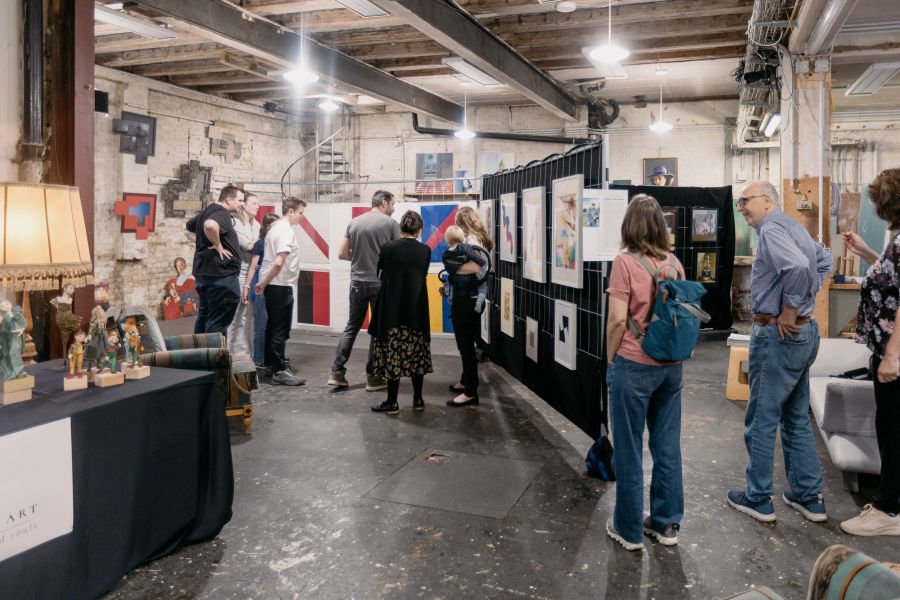 Besucher betrachten Kunstwerke in der Industriehalle des Schärferaums, im Vordergrund ein Tisch mit Skulpturen – KunstWerkStadt im Schärferaum Bad Homburg