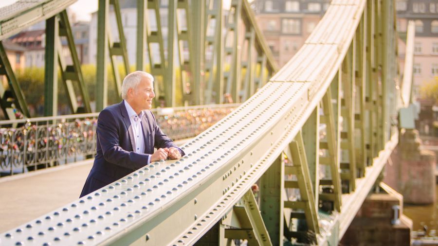 Ein Geschäftsmann im Anzug auf dem Eisernen Steg in Frankfurt bei Sonnenschein, für Union Investment. Fotografiert von dem Frankfurter Fotografen Fritz Philipp.