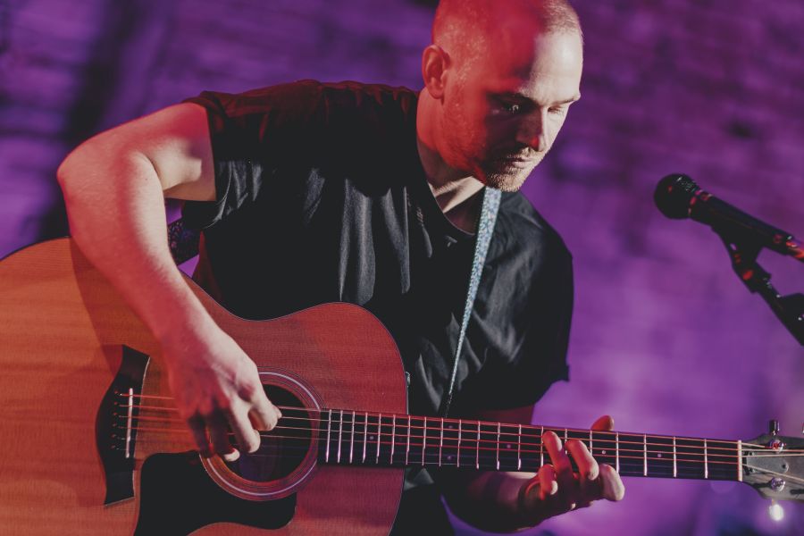 Gitarrist konzentriert an der Akustikgitarre – Sofakonzert von Die Dinners im Schärferaum