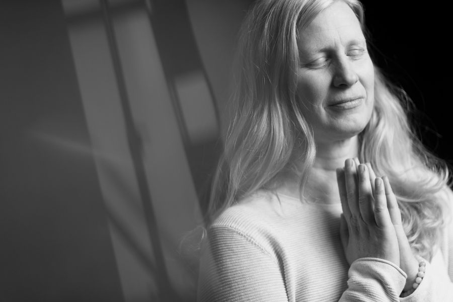 Schwarz-Weiß-Portrait einer Frau mit geschlossenen Augen, die lächelnd die Hände vor der Brust faltet – Schwarz-Weiß-Portrait bei der KunstWerkStadt im Schärferaum Bad Homburg