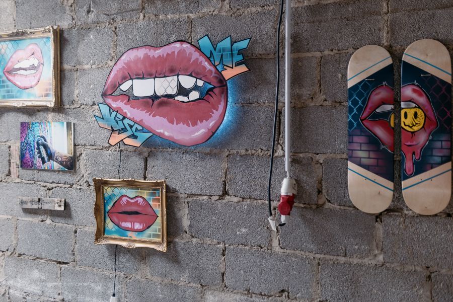 Pop-Art mit gemalten Lippen auf Leinwänden und Skateboard-Decks an einer grauen Steinwand – KunstWerkStadt im Schärferaum Bad Homburg
